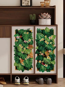 Dettaglio di adesivi murali 3D con foglie di monstera e fiori di plumeria su mobile bianco