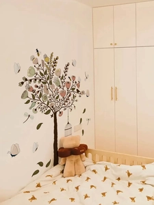 Detail of illustration style wall decal featuring tree, flowers, and a decorative birdcage