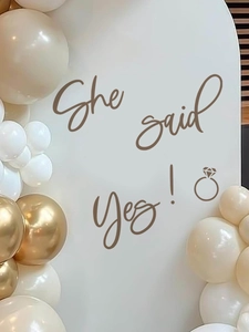 Close-up of 'She said Yes!' backdrop with champagne and gold balloons for engagement decor