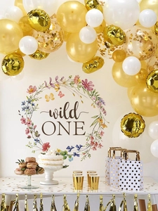 Close-up of Wild One themed first birthday party set with gold balloons and floral garland