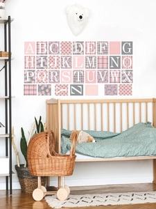 Nursery wall display of 26 alphabet PVC stickers with mixed patterns above a baby crib