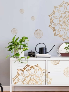 Makroaufnahme goldener Mandala-Wandaufkleber an einer modernen grauen Wohnzimmerwand