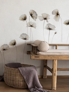 Détail de stickers muraux floraux translucides sur mur blanc avec banc en bois et panier