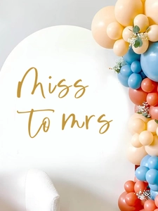 Detail of gold Miss to Mrs decal on white arch backdrop with party balloon garland