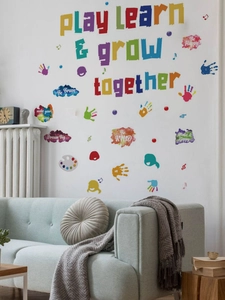 Détail du sticker mural 'Play Learn & Grow Together' avec motifs d'empreintes colorées