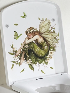 Detail of green butterfly fairy wall sticker applied on a white toilet lid surface
