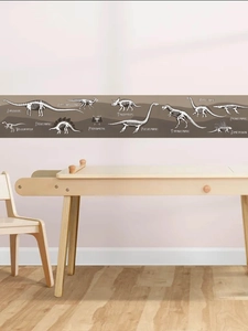 Detailed view of dinosaur fossil wall border on pink wall above a wooden desk