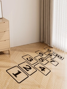 Detail of black numbered hopscotch floor stickers on light herringbone wood flooring