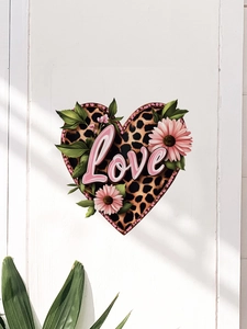 Close-up of leopard print heart wall sticker with pink flowers on white wooden wall
