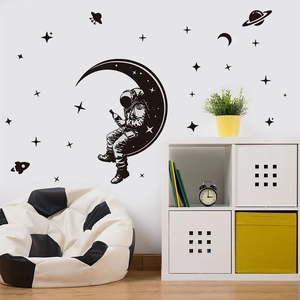 Black astronaut wall decal set with moon and stars in a modern cozy bedroom interior