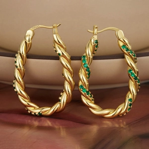 Détail du poinçon S925 sur boucles d'oreilles dorées torsadées avec zircons verts