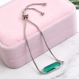 Macro view of adjustable silver box chain bracelet with oval green zircon crystal