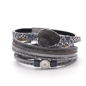 Detail van meerlaagse grijze lederen armband met kristalsteen en Romeinse bedelsteen
