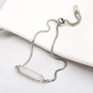 Macro detail of silver adjustable slider bracelet with oval white stone and box chain