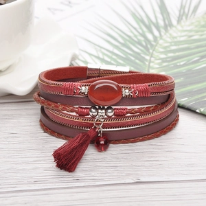 Detail of bohemian leather bracelet with red stone, silk tassel and magnetic clasp