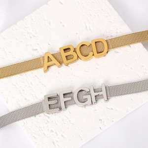 Détail des bracelets à maille dorés 18K et argentés avec des charmes alphabétiques