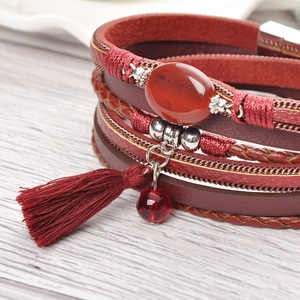 Macro detail of red layered leather bracelet with boho agate stone and cotton tassel