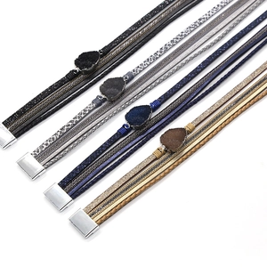 Detail van meerlaagse lederen armbanden met stenen bedeltjes en magnetische zilveren sluitingen