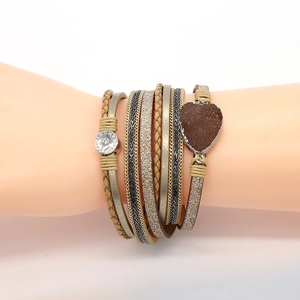 Detail van boho gelaagde armband met kaki gevlochten leer en hartvormige kristallen hanger
