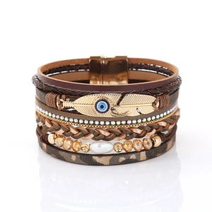 Detail of multi-layer leather bracelet with gold feather, evil eye charm and pearl detail