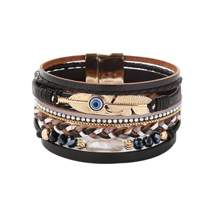 Detail of bohemian leather wrap bracelet with baroque pearl and evil eye feather charm