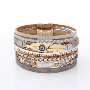 Detail of bohemian layered bracelet featuring a metal feather with the evil eye and magnetic clasp