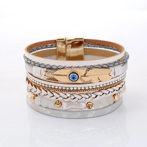 Detail of bohemian multilayer bracelet featuring gold feather charm and magnetic clasp