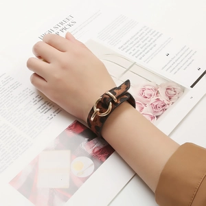 Gros plan d'un bracelet en cuir imprimé léopard avec un fermoir en métal doré poli au poignet