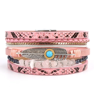Detail of pink snake pattern leather bracelet with silver feather and turquoise charm