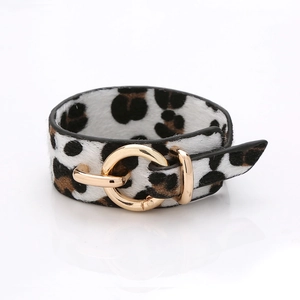 Détail du bracelet en cuir léopard à poils de poney avec un grand fermoir rond en métal doré