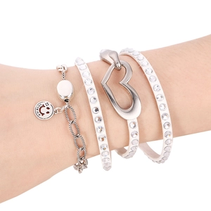 Macro shot of silver multilayer leather bracelet with diamond hearts and smiley charm