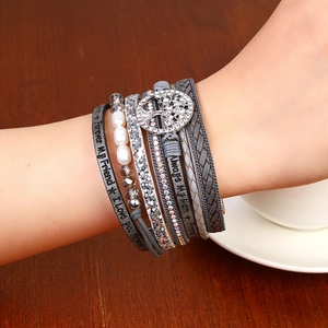 Detail view of rhinestone tree of life charm on a stylish multi-layer wrap bracelet