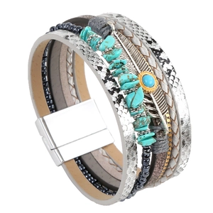 Detail of bohemian multilayer leather bracelet with silver feather charm and turquoise stones