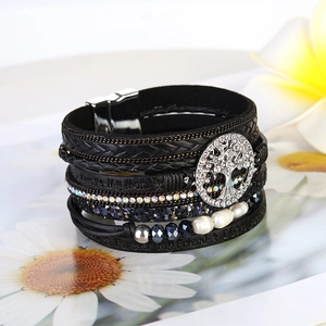 Detail of multi-layer leather bracelet with tree of life charm and magnetic clasp