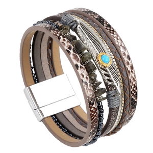 Detail of multilayer leather bracelet featuring a metal feather charm and magnetic clasp