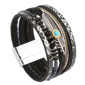 Detail of vintage layered leather bracelet with silver feather and turquoise charm