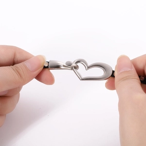 Detail of silver heart-shaped buckle and flexible black strap on a stylish woman's bracelet