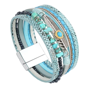 Detail of bohemian leather bracelet featuring turquoise beads and silver feather charm