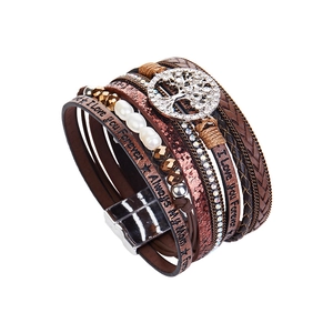 Close-up of leather wrap bracelet featuring a rhinestone Tree of Life charm and engraved text