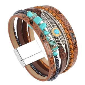 Close-up of layered leather bracelet with turquoise stones and silver feather charm detail
