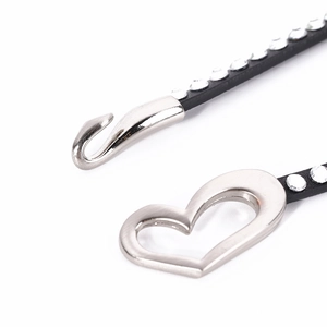 Close-up of black leather strap with rhinestones and silver heart-shaped metal buckle