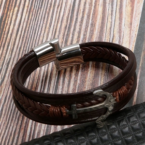 Detalle de la pulsera multicapa de cuero marrón con ancla plateada y un cierre magnético