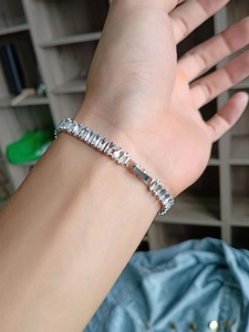 Primo piano di un bracciale tennis argento con zirconi a baguette indossato al polso