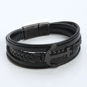 Detalle de la pulsera de cuero negro trenzado multicapa con amuleto de ancla y cruz