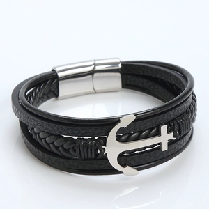Detalle del amuleto de ancla y cruz en pulsera de cuero negro de varias capas para hombre
