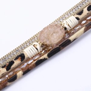Detail eines Boho-Armbands mit Leder im Leopardenmuster, Strasssteinen und rosa Kristall