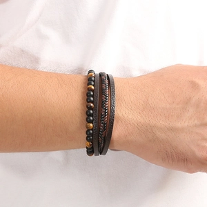 Détail d'un bracelet multicouche en œil de tigre et cuir tressé au poignet d'homme