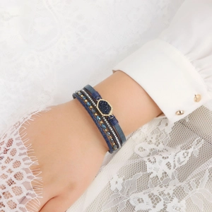 Detail of multi-layer wrap bracelet featuring dark blue leather and gold stone accents