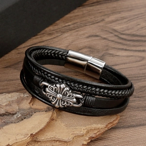 Détail du bracelet multicouche en cuir noir avec croix florale argentée et fermoir magnétique