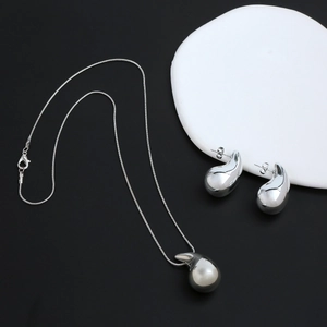 Detalle del conjunto de collar con colgante de gota y pendientes en acabado plata